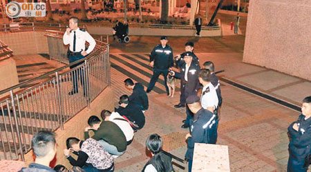涉案被捕男子蹲於街邊等候帶署。（林明強攝）