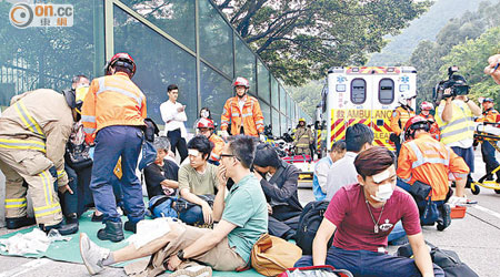 大批傷者被分流後坐在地上等候送院。（張世洋攝）