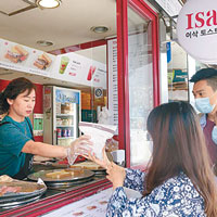 遊客在南韓食店買食物時戴上口罩，職員卻無防護措施。（中央社圖片）