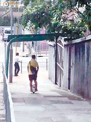 黃衣少年雙手插在褲袋騎着「風火輪」直衝落斜，有途人正從街頭另一面走出來。