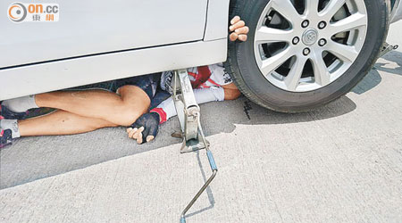 踏單車男子被壓在私家車底，一隻手夾在車輪與沙板之間。（fb小心駕駛群組提供）