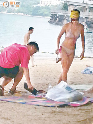 馮煒光與女伴一起在沙灘曬日光浴。（讀者提供）