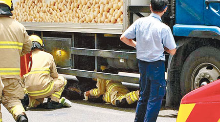老婦被貨車捲入車底，消防員進行拯救。（互聯網圖片）