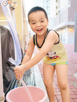 葵聯邨一男孩從街喉取得清水後，展露燦爛笑容。（黃嘉儀攝）