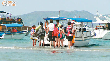遊人要赤腳涉水走到淺灘中登船，人人手提行裝避免弄濕。