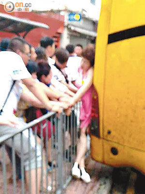 女遊客被夾在旅巴與鐵欄之間，途人與團友合力拉扯鐵欄救人。（網民黃順發提供圖片）