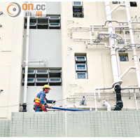工程人員在欣安邨欣悅樓平台做水管接駁工作。
