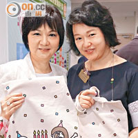 馮少雲（左）及文穎怡手持本地插畫師為東華設計嘅布袋。