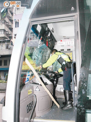直通巴擋風玻璃遭竹枝插穿碎裂，警員在巴士內調查。（賴南秋攝）
