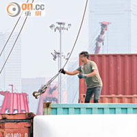 在昂船洲公眾貨物裝卸區，一名工人在操控繩索時未戴上安全設備。