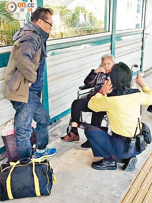 老婦獲救後在月台坐在輪椅上，港鐵職員上前慰問。（讀者提供）