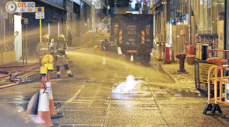 消防員向噴出路面的火燄射水。（王偉安攝）