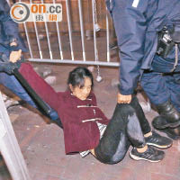 女示威者被警員帶走時坐在地上。