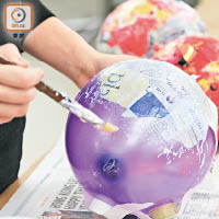 利是封再造錢罌做法簡單，以白膠漿將一層層報紙及利是封貼上氣球。