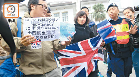 區先生與友人在禮賓府內高舉印有英國標誌雨傘及展示政治性標語。（袁志豪攝）
