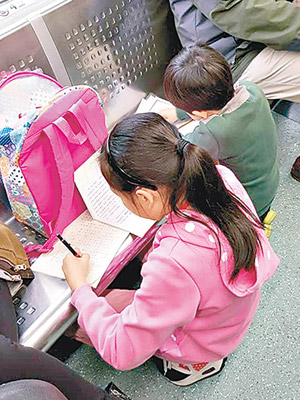 有網民攝下小學生在港鐵車廂趕功課。（互聯網圖片）
