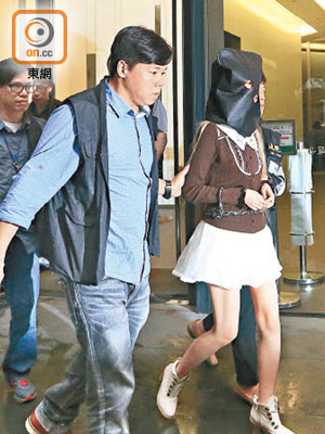 姓何女疑犯身穿短裙高踭鞋，被警員押返荃灣工廈。（陳章存攝）