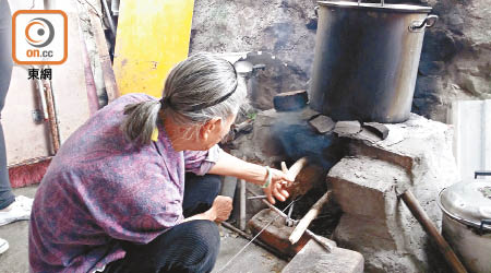村民燒柴煮食，生活十分原始。（潘嘉寶攝）