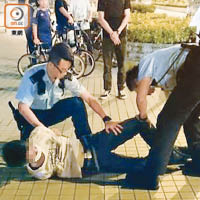 青年被押上警車時反抗，再遭警員制服在地上。（讀者提供）