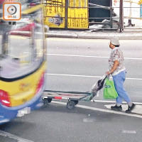 中環<BR>與車擦身<BR>工人在馬路上逆線推車，與巴士擦身而過。