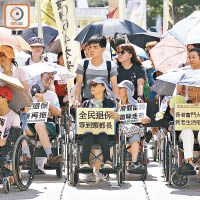 大批長者坐輪椅在酷熱天氣警告下遊行，爭取無經濟審查的退保方案。