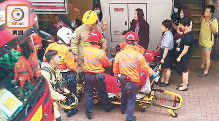 不適的東亞女職員由救護員扶上擔架床送院。