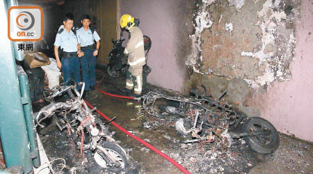 被縱火電單車燒成爛鐵，警方及消防員在場調查。（楊偉嶽攝）