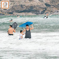 一名家長帶同小朋友到大浪灣泳灘滑浪。