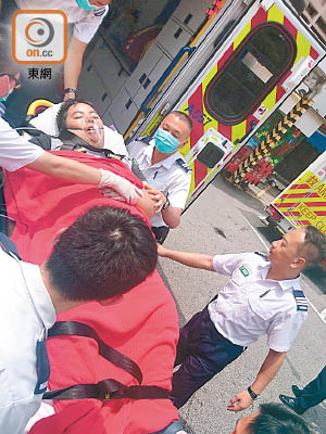 肥胖少年由六名救護員合力抬落救護車。