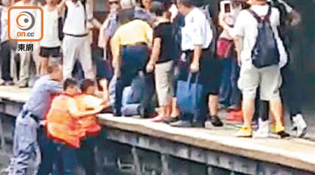 穿橙色反光衣的港鐵職員，疑用拳打闖路軌男的腰及腿部。（讀者提供）