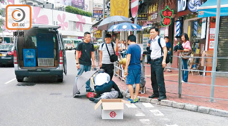 診所醫生為傷者施救，街坊在旁打傘。（讀者提供）