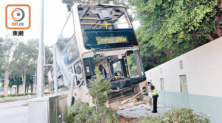 巴士失控剷上石壆，車頭損毀嚴重。（張曉楠攝）