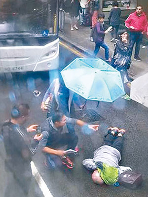 屈醫生為傷者急救，市民在旁撐傘擋雨。（互聯網圖片）