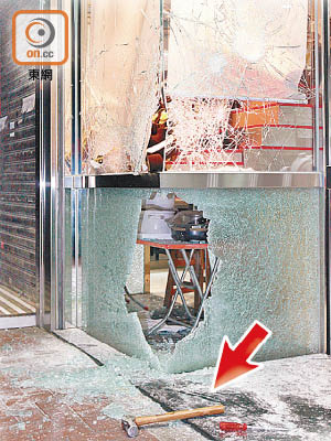 玻璃櫥窗被扑爆地上遺下一柄鐵錘（箭嘴示）。（吳建明攝）