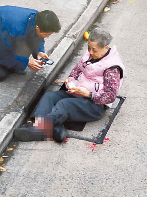 被輾斷腳老婦坐在路旁待救。（互聯網圖片）