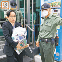 曾慶淳（左）兩手抱着裝滿物資的大膠袋到收押所。