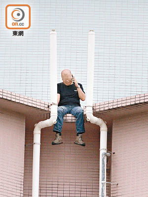 企圖跳樓男子在大廈天台危坐。（曾紹良攝）