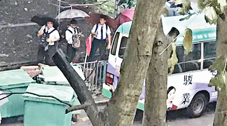 香港<br>一班穿着校服的學生，撐起雨傘，在暴雨下默默苦等。（互聯網圖片）