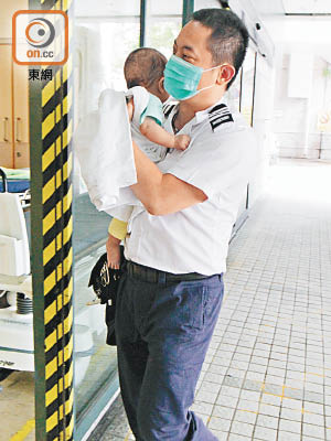 男嬰由救護員抱着送院。（梁裔楠攝）