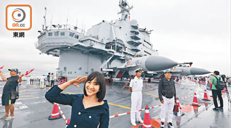 有美少女興奮地登上遼寧號甲板後，在殲15戰鬥機前模仿女兵敬禮留影。