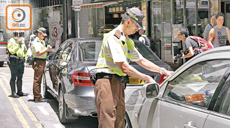 違泊黑點之一，銅鑼灣景隆街不少車輛停泊在雙黃線及禁區位置，警員即時票控。（袁志豪攝）