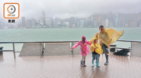 有市民帶同小朋友穿齊雨衣水靴在尖沙咀海旁追風。（高嘉業攝）