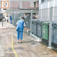 清潔工人用水喉噴灑垃圾桶及街道，清除污漬。