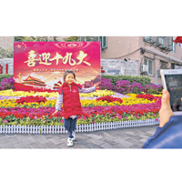 北京<br>市民在北京街頭「喜迎十九大」花壇前留影。（中新社圖片）