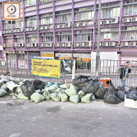 葵涌<br>葵涌石文徑停車場一幅警告切勿非法棄置廢物的橫額下，堆滿大包小包建築廢料。