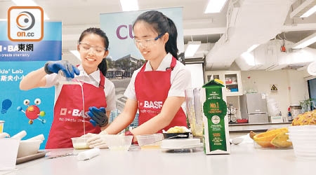 衛樂婷（右）和許昕喬（左）在中大化學實驗室示範簡單實驗製作薑汁撞奶。（林祐權攝）