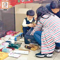 羅湖商業城內，不少家長在地上攤開貨物，幼童在旁協助將貨物放入包裝盒內。