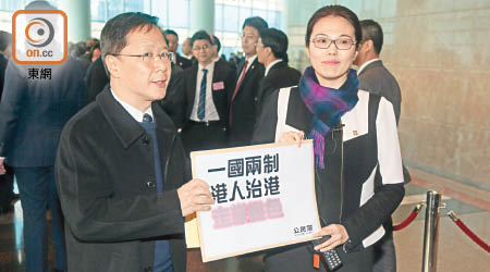 郭家麒（左）將印有「一國兩制 港人治港 走樣變色」的公文袋交予中聯辦職員後便離去。（徐家浩攝）