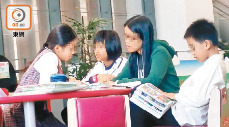 一名「家長導師」為多名學童批改功課及溫習默書。