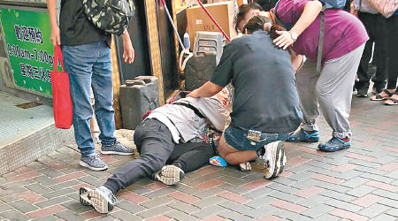男傷者倒臥地上，熱心途人上前慰問。（互聯網圖片）